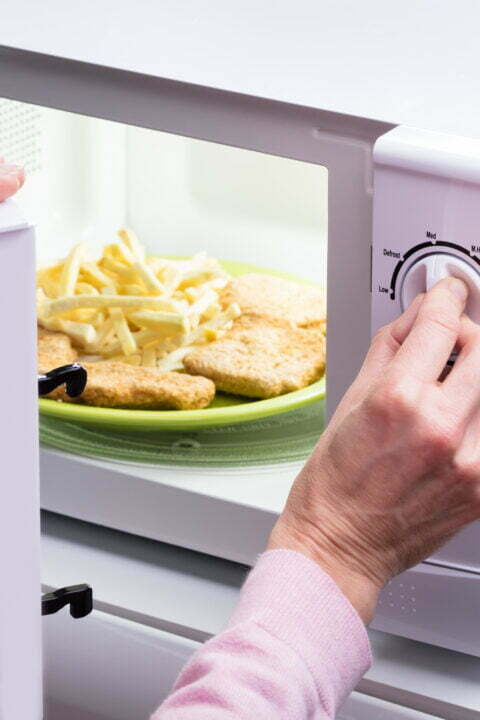 Woman Heating Food In Microwave
